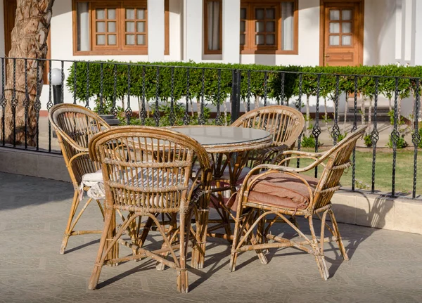 Wooden rotan chairs and a round table on the background of the r — Stock Photo, Image