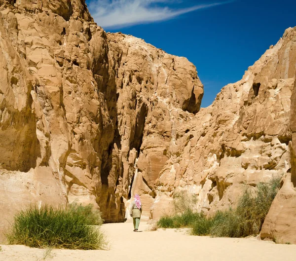 Beduin na biało idzie w kanionie na pustyni wśród skał — Zdjęcie stockowe