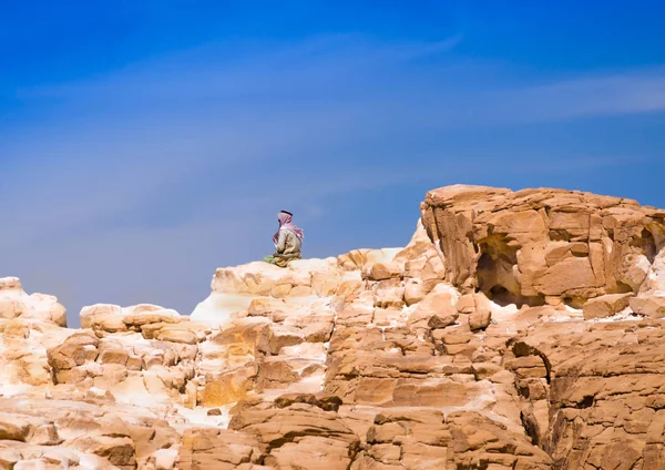 Bédouin assis sur le sommet d'une haute roche de pierre contre un bleu — Photo