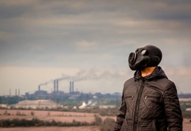 fabrika borularından duman ortasında bir gaz maskesi adam