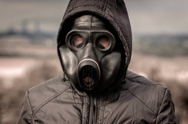 bir gaz maskesi ve fabrika borularından duman arka plan karşı bir başlık bir adam portresi