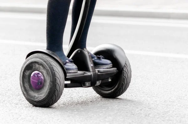 Женские ноги на электрическом скутере на городской улице вблизи — стоковое фото