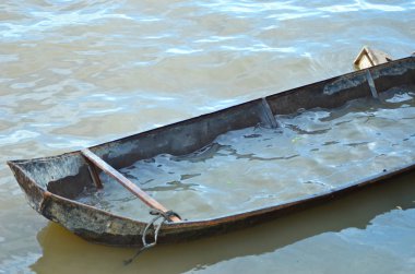 Eski bir teneke tekne bir çamurlu nehir üzerinde yarım su ile dolu ve demirli. Olay yerini terk edilmiş. Tekne paslı ve görünüyor sanki batmaya abut.