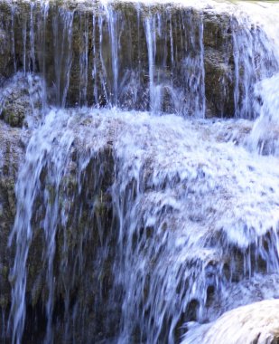 Bir şelale temiz su kahverengi kayalar üzerinde aşağı yuvarlanıyor. Uzun bir pozlama, küçük beyaz yaylar olarak görünür su damlaları ile, mavi-beyaz bir akan levha gibi su görünmesini sağladı.