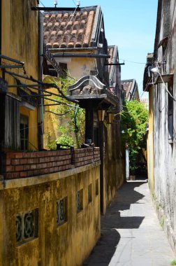 Sarı bir duvar bir yan sokakta Hoi aşağı çalışan bir, bir kapı üzerinde bir kemer ile. Sarı eski binalar ve ağaçlar cadde kuyruğu. Gökyüzü mavidir. Sokakta terk edilmiş.