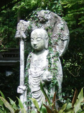 Gri taş Buda, Japon bir dini heykeli. Heykel bir elinde bir top ve bir kutup başka bir tutar. Heykelin üzerine sondaki üzüm var. Arka plan ağaç ve çalı formu.
