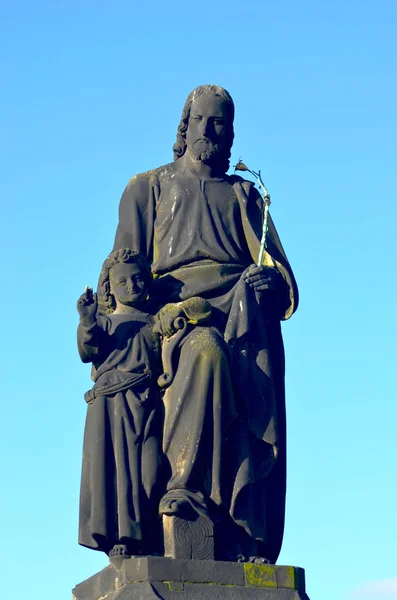 在布拉格的查尔斯桥上 圣约瑟夫和一个年轻的基督的户外雕像 他拿着一根花杆 背后的天空是蓝色的 — 图库照片