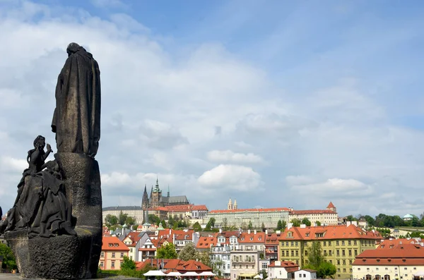 Bir heykel Charles Köprüsü, Prag tetikte duruyor. Arkasında şehir Prag Kalesi'ne doğru bir görünüm bitti. Giderek kötüleşen fırtına bulutları ile Gökyüzü mavidir.