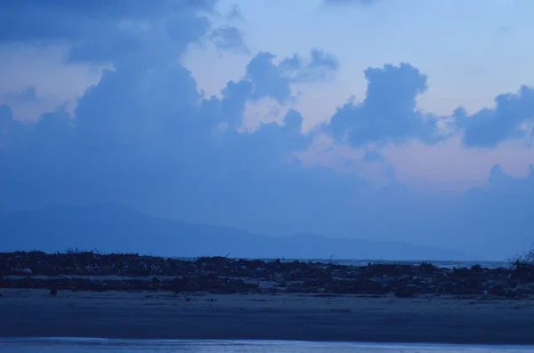 Sunrise, bulutlar gökyüzü, tüm mavi tonlarında doldurma ile bir plaj. — Stok fotoğraf