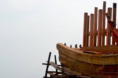 Bulutlu bir gökyüzüne karşı hala yapım aşamasında olan ahşap bir teknenin çerçevesi.