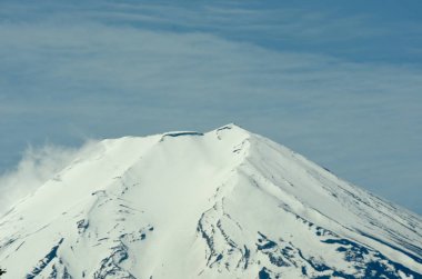 Fuji Dağı'nın karla kaplı zirvesi bulutlu bir gökyüzüne karşı görülüyor.