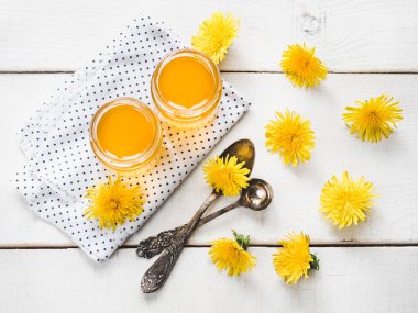 Sarı, parlak dandelions, güzel, beyaz, ahşap bir tablo üzerinde bir kavanoz bal çiçek. Üstten görünüm, yakın çekim. Bir lezzetli ve sağlıklı yemek kavramı