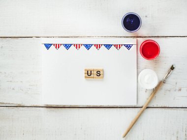 Kart ABD bayrağı, bir desenle kelime bize ve renkli guaj boyalar Beyaz, vintage, ahşap bir masaya. Üstten görünüm, yakın çekim. Bir bağımsız, güçlü bir ülke ve ulus kavramı