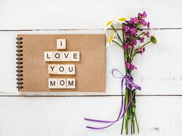 アルファベットと単語のママ ビンテージの白い木製のテーブルに野の花の花束の木製の文字とメモ帳 平面図 クローズ アップです 幸せな家族の概念 — ストック写真