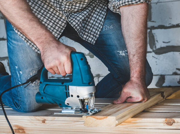 Strong men's hands and tools for working with wood inside the house under construction. Concept of construction and repair