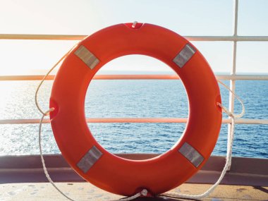 Parlak, turuncu lifebuoy cruise liner dalgalar deniz ve sabah güneşin arka plan üzerinde üst güvertede. Güvenlik, bakım ve yardım kavramı