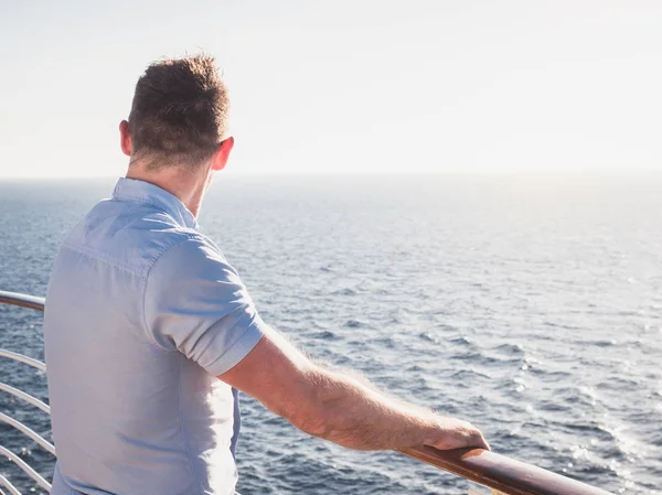 Çekici erkek güneş gözlüğü mesafe bir gün batımı arka planı içine bakan gemisi üst güvertede. Deniz seyahat ve eğlence kavramı