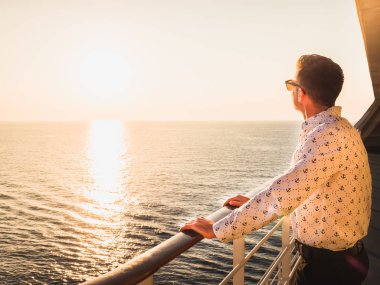 Gün batımı bir arka plan üzerinde mesafe bakarak çapa gemisi, üst güvertede şeklinde desenleri ile çekici adam beyaz gömlekli. Deniz tema. Deniz yolculukları ve dinlenme kavramı