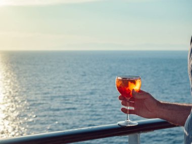 Bir bardak güzel pembe kokteyl bir Cruise açık bir güvertede erkek el günbatımı, dalgalar deniz bir arka plan üzerinde gemi ve gökyüzü temizleyin