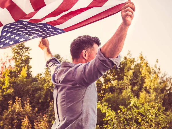 Привлекательный мужчина машет на ветру флагом США — стоковое фото