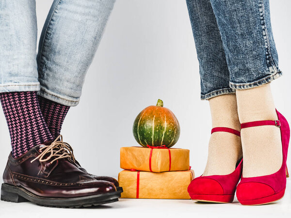 Ripe pumpkins, legs of a young couple in stylish shoes, bright, colorful socks. White background, isolated, close-up. Holidays, fashion, elegance