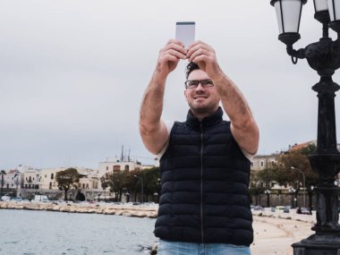 Arka plan bir denizin üstünde a telefon ile şık, mutlu bir adam