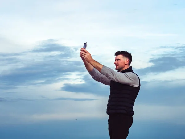 Fashionable, attractive guy with a phone on the background of sea