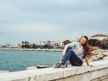 Bulutlu bir günde dalgalar deniz ve kıyı şeridi fon karşı mesafe bakarak zarif, şirin kadın