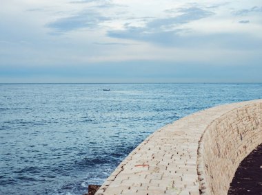 Deniz Körfezi ve taş iskele mavi, bulutlu gökyüzü arka plan üzerinde