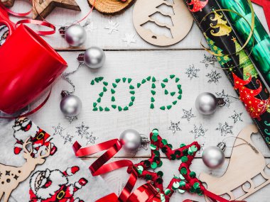 Mutlu yeni yıl tebrik kartı. Renkli Noel süsleri ve oyuncak, sıcak Noel Baba, kırmızı bir kupa ile çorap ve bir beyaz, ahşap yüzeye şerit. Görünümü, yakın çekim top, yat
