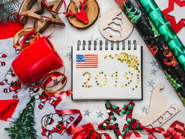 Mutlu yeni yıl tebrik kartı. Renkli Noel süsler ve ABD bayrağı, sıcak çizim oyuncak, Noel Baba ile kırmızı kupa çorap ve bir beyaz, ahşap yüzeye şerit. Görünümü, yakın çekim top, yat
