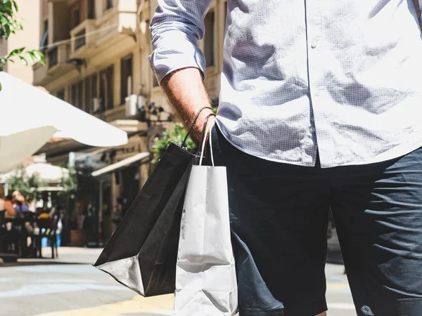 Stylish man with two bags on the street in summer, sunny day. Concept of style, fashion and beauty