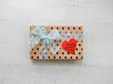 Tatlı sözler sevgi ve tinsel kalp şeklinde bir notla bir kurdele ile bağlanmış bir hediye ile kutu. Üstten görünüm, yakın çekim, düz yatıyordu, izole arka plan. Sevgililer günü için hazırlanıyor