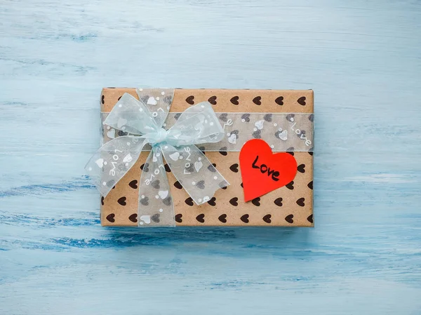 Box with a gift, tied with a ribbon, note with sweet words of love and tinsel in the shape of hearts. Close-up, flat lay, isolated. Congratulations for loved ones, relatives, friends and colleagues