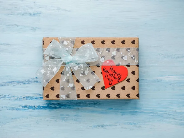 Box with a gift, tied with a ribbon, a note with sweet words of Love and tinsel in the shape of hearts. Top view, close-up, flat lay, isolated background. Preparing for Valentine\'s Day