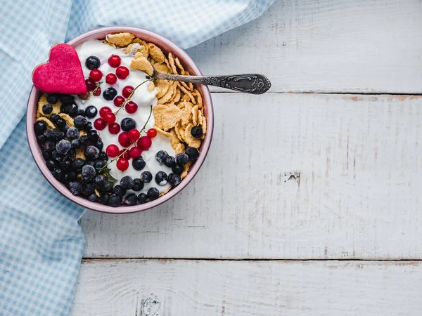 Healthy breakfast. Cereal biscuits in pink glaze, cornflakes, yogurt and fresh berries on the background of white boards. Close-up, top view, isolated. Concept of healthy and delicious food