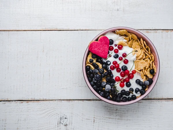 Healthy breakfast. Cereal biscuits in pink glaze, cornflakes, yogurt and fresh berries on the background of white boards. Close-up, top view, isolated. Concept of healthy and delicious food