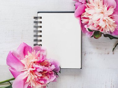 Parlak peonies, ahşap bir masa boş Not Defteri sayfası