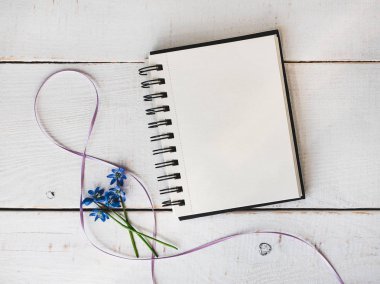 Sketchbook, boş sayfa, parlak çiçek, pembe kurdele kurulların beyaz bir tablo. Üstten görünüm, yakın çekim. Tebrikler sevdiklerini, Aile, arkadaşlar ve iş arkadaşları için