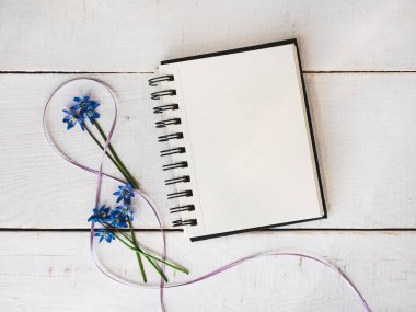 Sketchbook, boş sayfa, parlak çiçek, pembe kurdele kurulların beyaz bir tablo. Üstten görünüm, yakın çekim. Tebrikler sevdiklerini, Aile, arkadaşlar ve iş arkadaşları için
