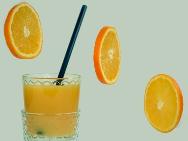 新鮮なオレンジ ジュース 白にオレンジ スライスを飛んでガラスは 背景を分離しました クローズ アップ おいしいと健康食品のコンセプト — ストック写真