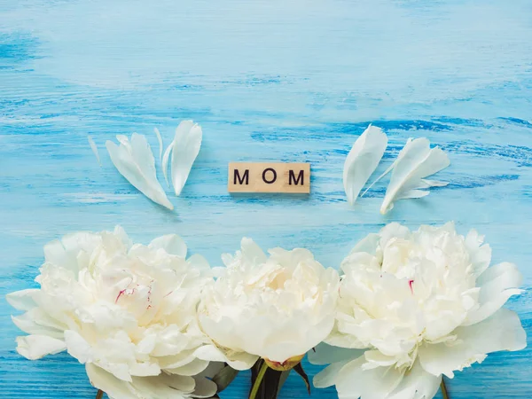 美しい花は 青の背景に母の愛の言葉で アルファベットの木製文字 平面図 クローズ アップです 幸せな家族の概念 — ストック写真