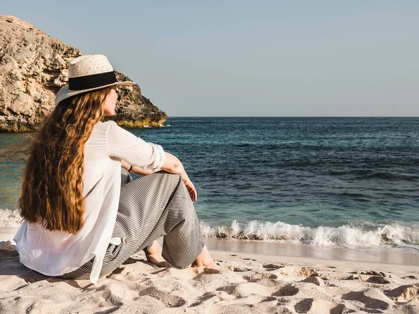 Mujer linda sentada en una playa vacía — Foto de Stock