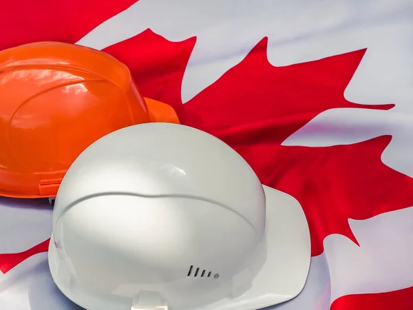 Canadian flag and two protective hardhats. Close-up — Stock Photo, Image