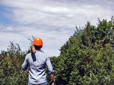 Parkta yeşil ağaçların arka planında elinde balyoz tutan çekici bir adam. Yakın plan. Çalışma ve istihdam kavramı