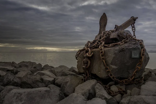 The old anchor on a large stone with a chain. Keflavik Iceland July 2016