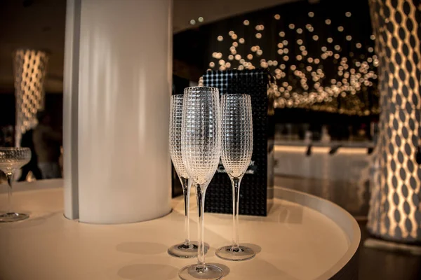 A number of glasses stand on a long table, prepared for champagne.