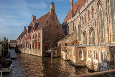 Genç bir adam beyaz kuğu tarafından çevrili bir ahşap köprü kız arkadaşına fotoğraflar. Belçika, Bruges 16 Ekim 2018