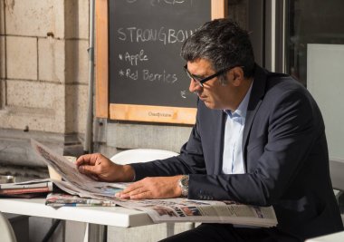 Yakışıklı bir adam bir kafede oturur ve sabah gazeteleri için bakar, bir fincan kahve. Belçika 12 Ekim 2018 tarihinde Leuven şehridir.