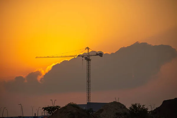 Tower crane at a construction site at sunrise. The beginning of the working day.